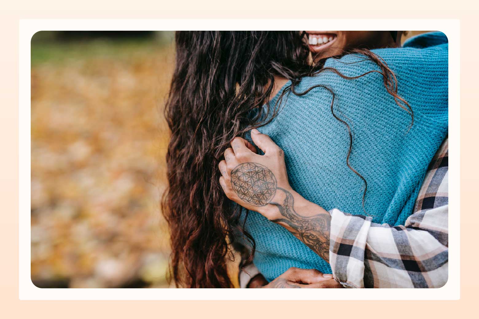Cropped image showing only the back of one person and the tattooed arm and smile of another person as they embrace