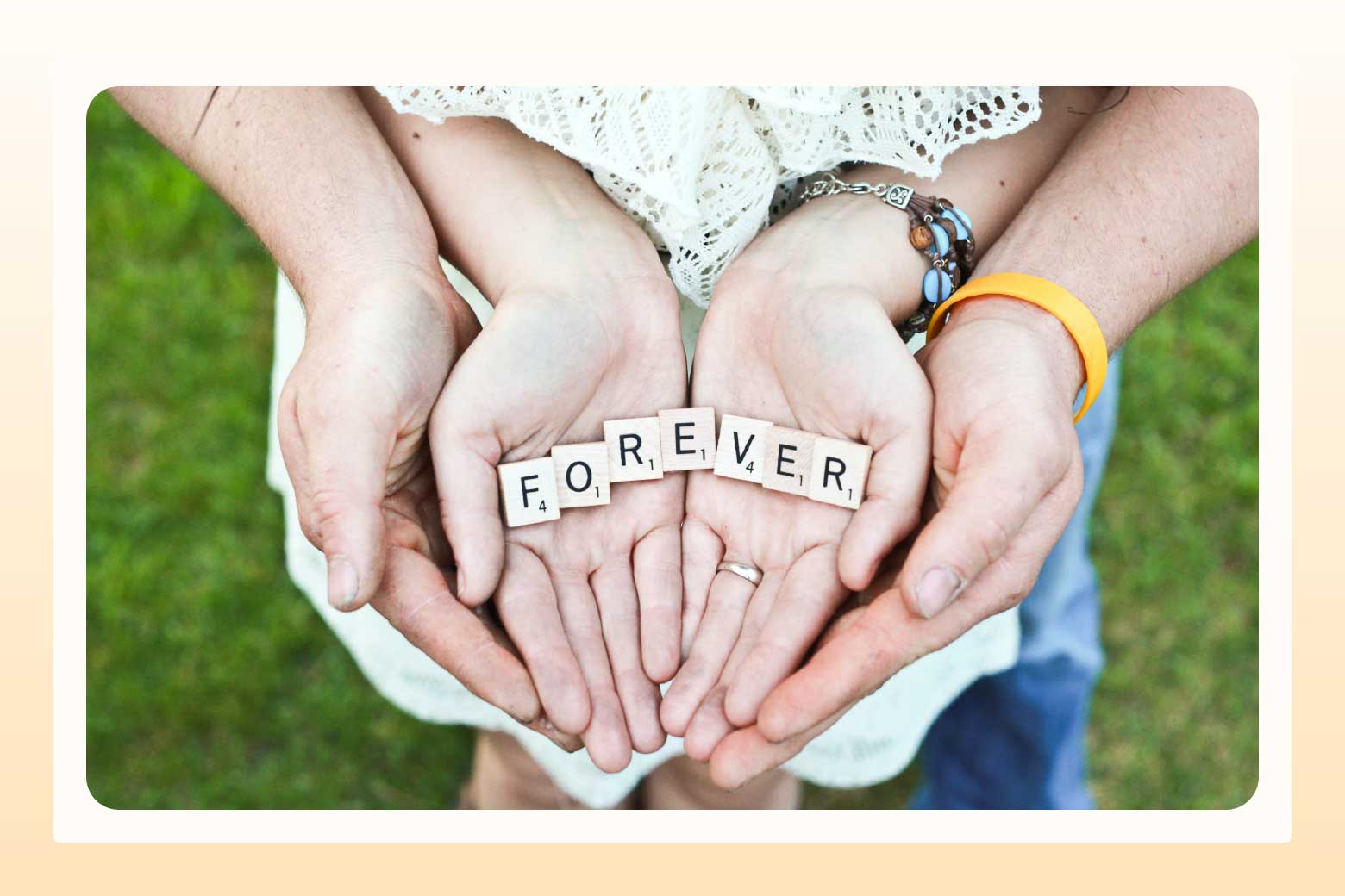 Two sets of hands holding their palms open and stacked, with Scrabble tiles spelling out forever in their palms