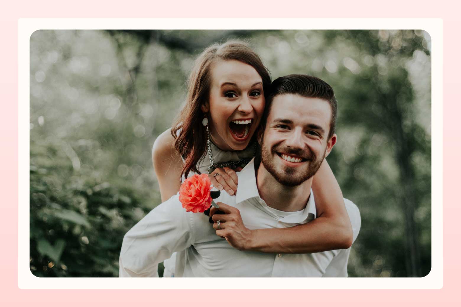 Laughing woman holding a pink flower piggybacking on a smiling man
