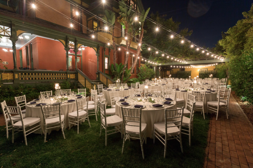 reception setup with white tablecloth tables under twinkle lights at night at britt scribbs manor in san diego