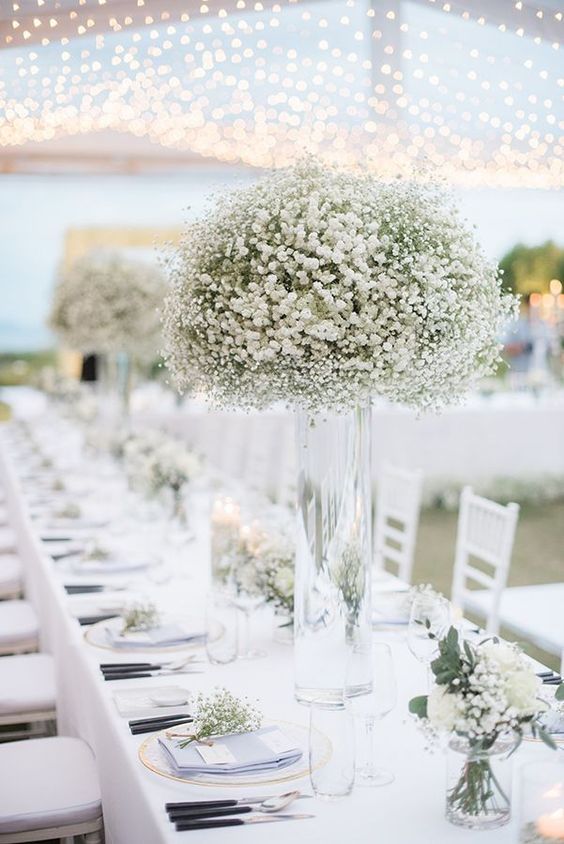 white flowers in a clear tall vase at a wedding reception table