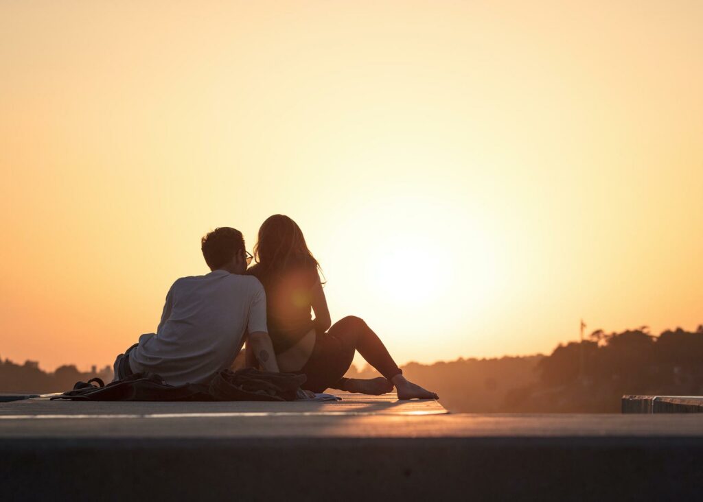 A couple sitting on a rooftop deck near trees during golden hour