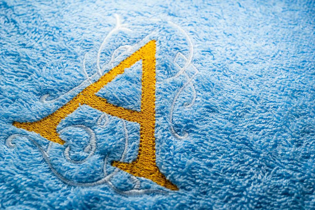 Wedding favor gift idea: A close-up of a monogrammed beach towel with the letter A in bright stitching