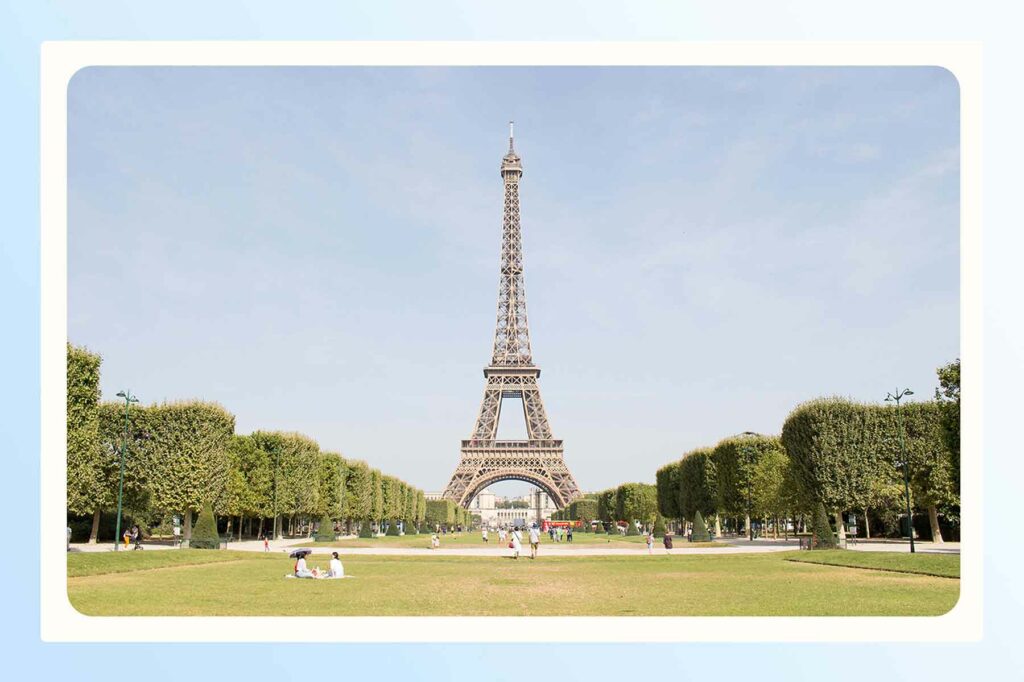 The Eiffel tower during the day, framed by tall tree groves on each side