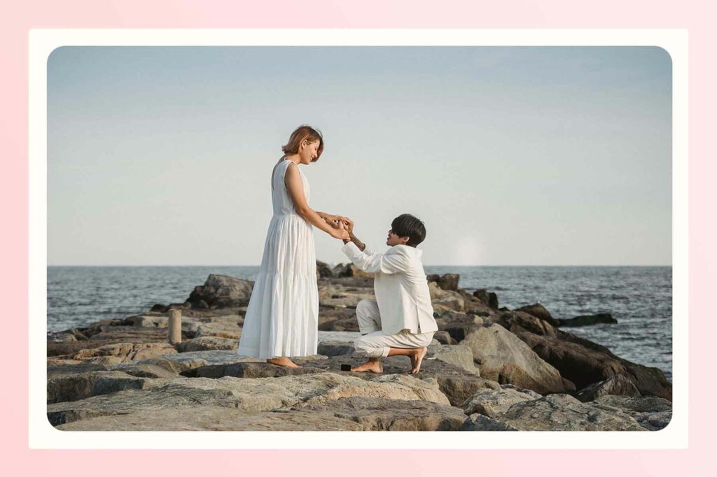 A couple getting engaged on a rock in a waterfront destination