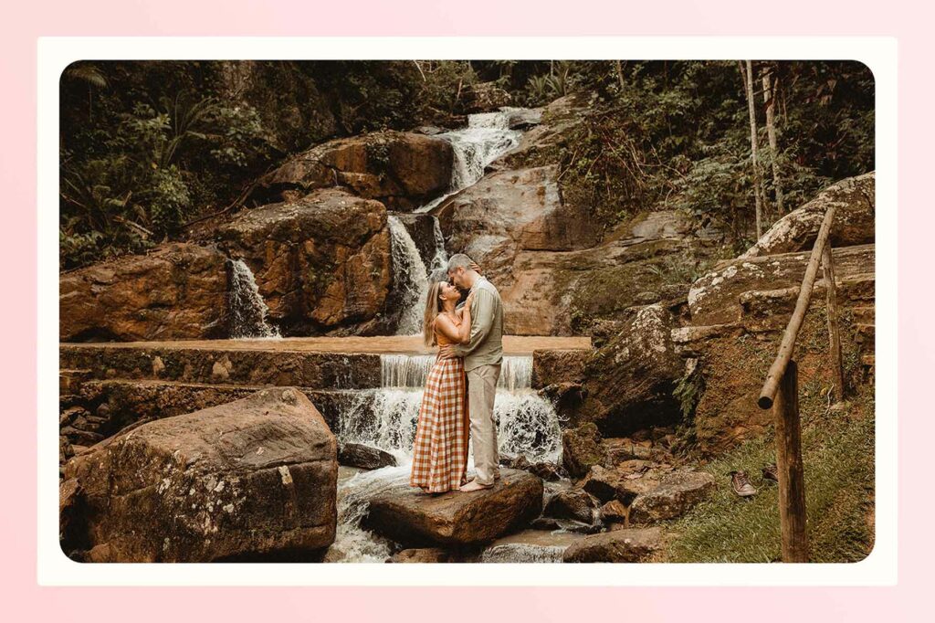 a man and woman embracing in front of a waterfall
