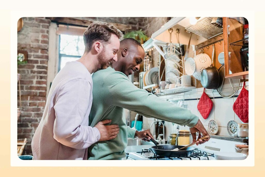 A couple cooking in a kitchen with a fry pan and a spatula