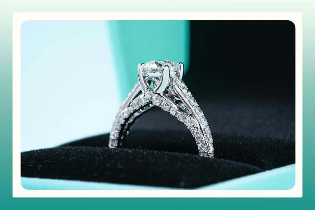 A close-up of a diamond engagement ring in a ring box, with diamonds detailing the bottom of the ring