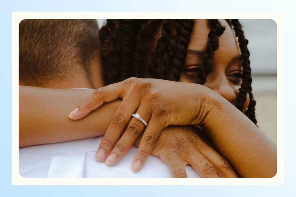 A woman embracing a man with a focus on her new engagement ring