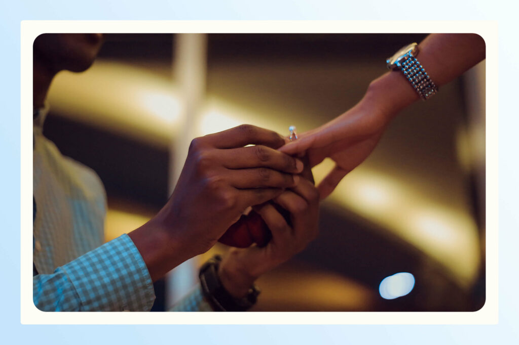 A man sliding a ring onto a woman's finger during a proposal