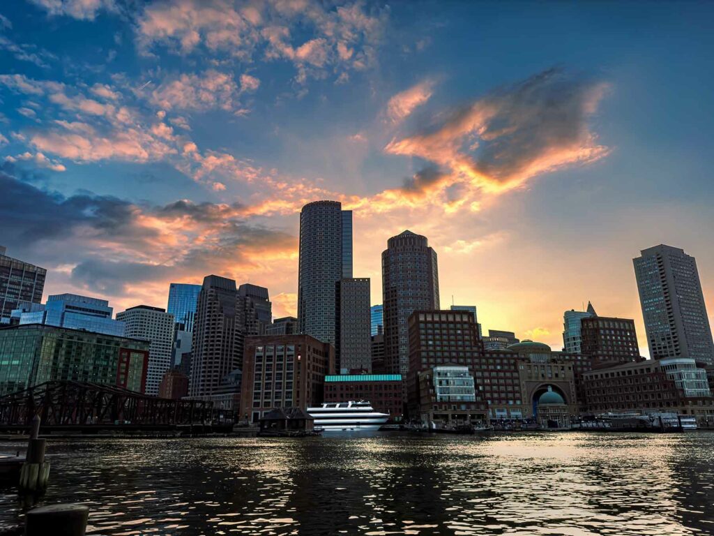 Boston engagement photo location at Fan Pier Park with a waterfront and building skylines at sunset