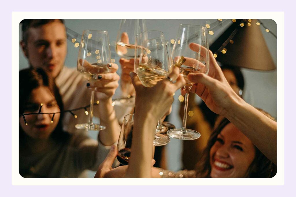 Several people holding a glass of wine in cheers at an engagement party