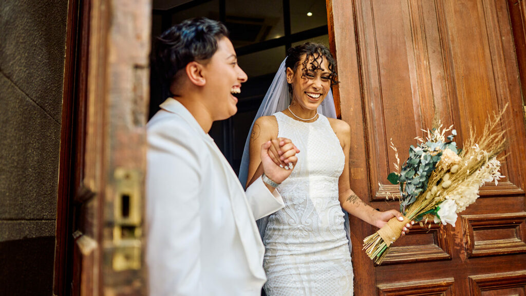 two newly weds walking out of a wedding venue together.