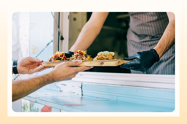 a person at a food truck handing an order to a wedding guest